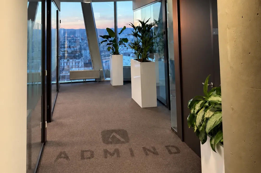 Flur im ADMIND-Büro in Wien mit Blick über die Stadt, im Teppich das ADMIND-Logo